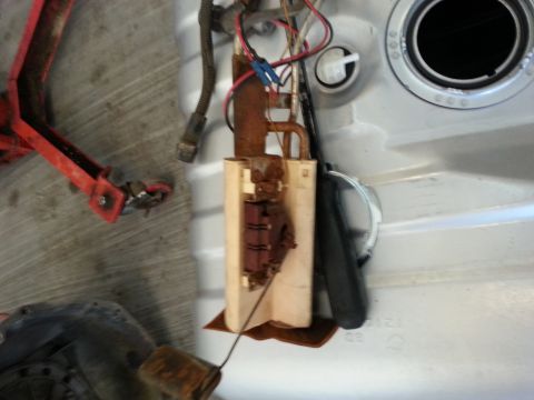 1994 Ford Bronco - Fuel pump assembly removed from inside a fuel tank, showing wiring and hoses connected.