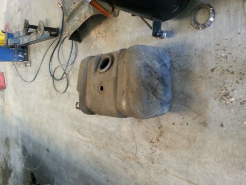 1994 Ford Bronco - A detached fuel tank sits on a garage floor, possibly awaiting installation or repair.