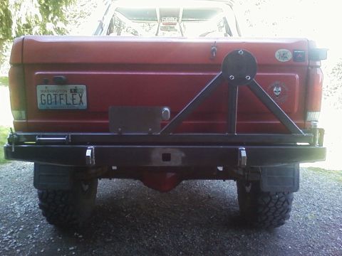 1989 Ford Bronco - Rear view of a red Ford Bronco, likely from the 1980s, with a custom bumper and spare tire mount.