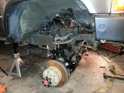 1987 Toyota 4Runner - The front suspension of a vehicle is disassembled and supported by jack stands in a garage.