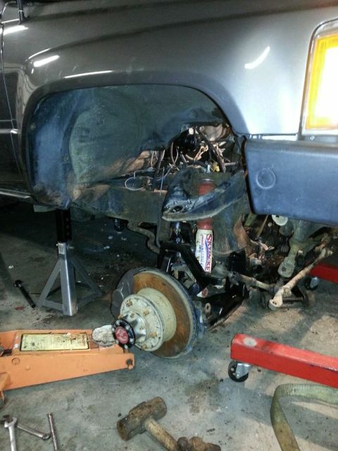 1987 Toyota 4Runner - The front suspension and wheel assembly of a vehicle are disassembled, with various tools and support equipment visible.