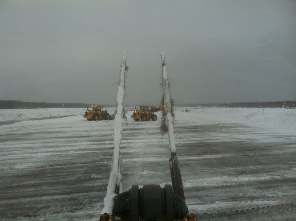 Two yellow wheel loaders in a snowy field under an overcast sky