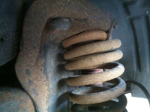 1989 Ford Bronco - This image shows a heavily rusted suspension coil spring and surrounding metal parts.