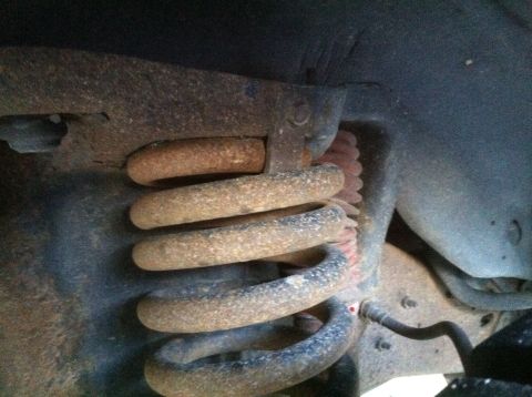 1989 Ford Bronco - Close-up of a rusty suspension coil spring, part of a vehicle's undercarriage.