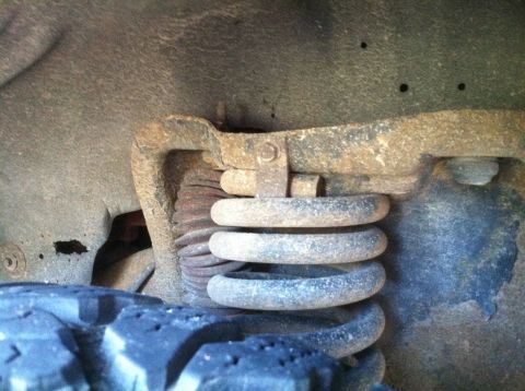 1989 Ford Bronco - Close-up of a vehicle's front suspension coil spring and tire tread.