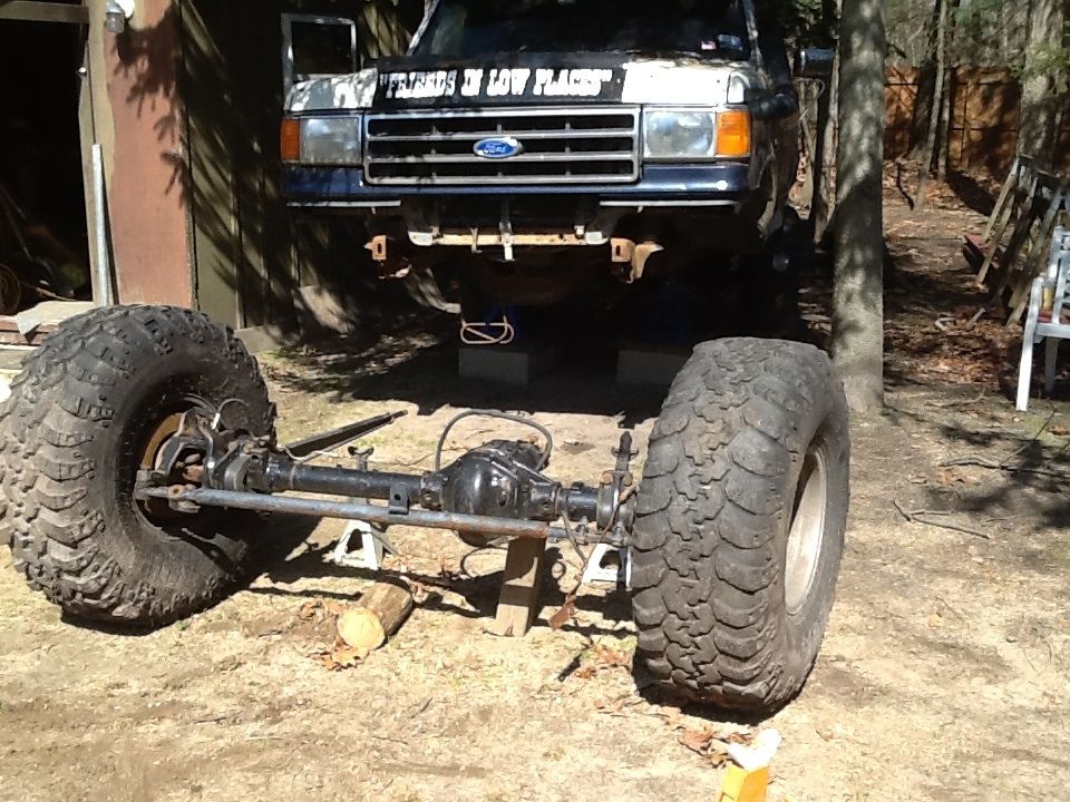 Ford truck with custom suspension and large tires, lifted off the ground