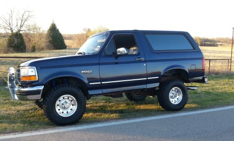 1995 Ford Bronco - This lifted 1995 Ford Bronco is shown in a three-quarter front view, parked on the side of a road.