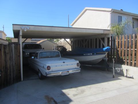 1968 Ford Mustang - A white pickup truck is parked under a carport next to a boat on a trailer.