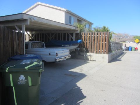 1968 Ford Mustang - A white pickup truck and a boat are parked under a carport on a sunny day.