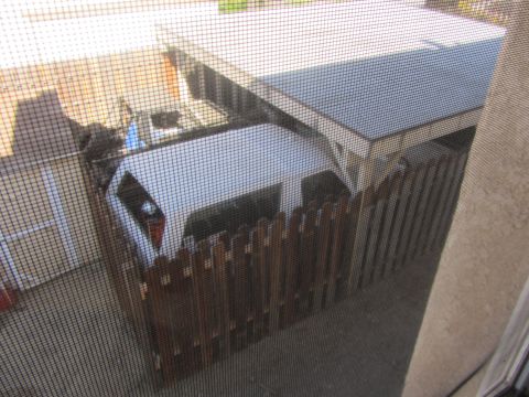 1968 Ford Mustang - A white minivan is parked under a carport, partially obscured by a wooden fence and a screen.