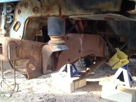 1989 Ford Bronco - Vehicle frame and suspension parts are rusted and supported by jack stands.
