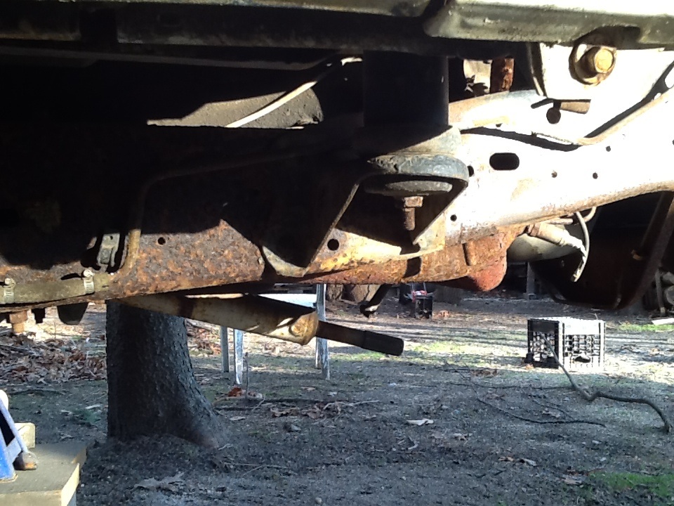 rusted vehicle frame and suspension components, exhaust pipe visible