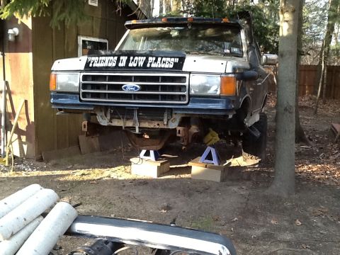 1989 Ford Bronco - This Ford truck is raised on jack stands in a yard, undergoing some work.