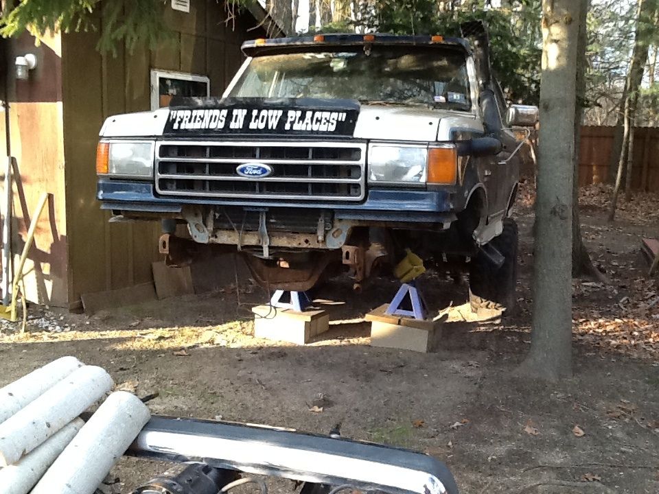 Ford truck on jack stands, has "FRIENDS IN LOW PLACES" on windshield