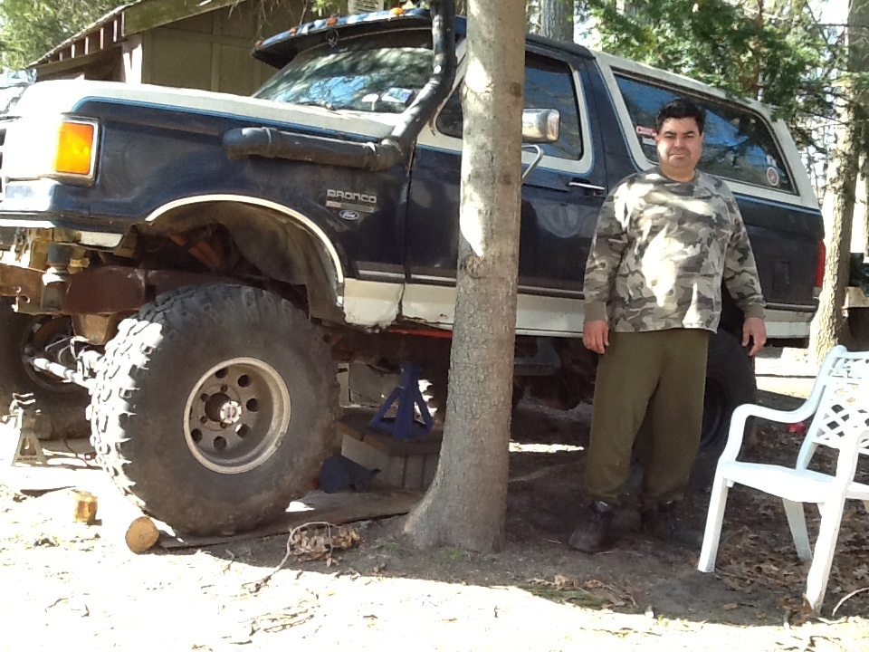 Dark blue 1989 Ford Bronco with snorkel and large tires, lifted and on jacks