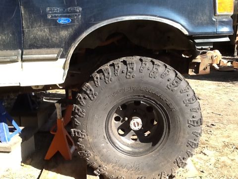 1989 Ford Bronco - A lifted Ford Bronco with large tires is shown supported by jack stands, indicating it is undergoing maintenance or modification.