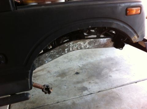 1987 Suzuki Samurai - Close-up of the front axle and suspension of a 1987 Suzuki Samurai, with visible modifications to the frame.