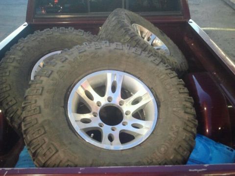 1994 Ford Bronco - Off-road tires and rims are loaded into the bed of a pickup truck.