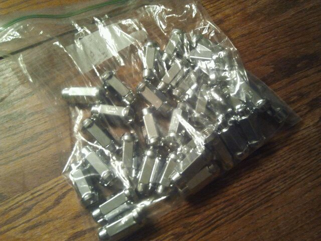 Bag of chrome lug nuts on wooden surface