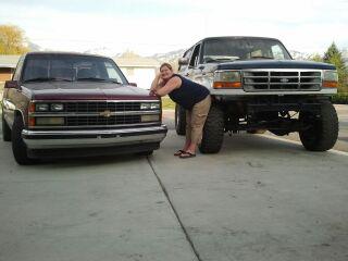 1994 Ford Bronco - A woman poses with two trucks, a Chevrolet pickup and a Ford truck, parked side-by-side.