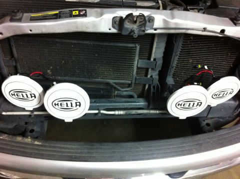 2005 Dodge 1500 - Aftermarket Hella fog lights are attached to the front grille area of a vehicle.