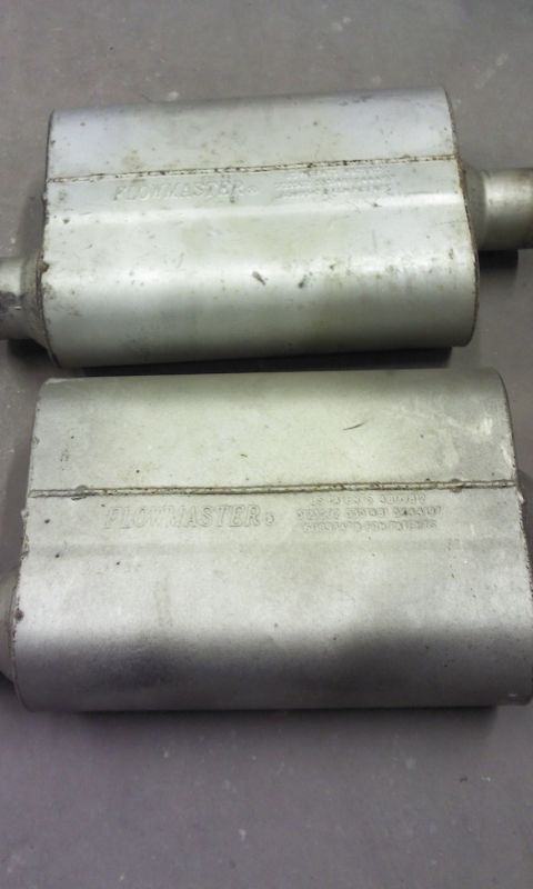 1967 Ford F-100 - Two Flowmaster mufflers are shown from a top-down perspective on a concrete surface.