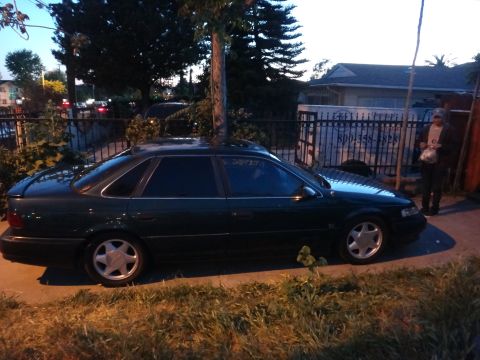 1993 Ford Taurus - A dark green 1993 Ford Taurus sedan is parked on the side of the road.