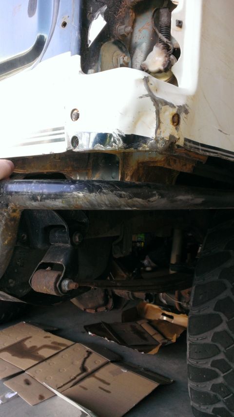 1994 Ford Bronco - Close-up view of the rear bumper and suspension system of a white SUV, showing signs of rust and damage.
