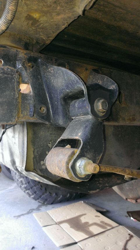 1994 Ford Bronco - Close-up of a rusty rear suspension component on a vehicle frame, with a tire visible.
