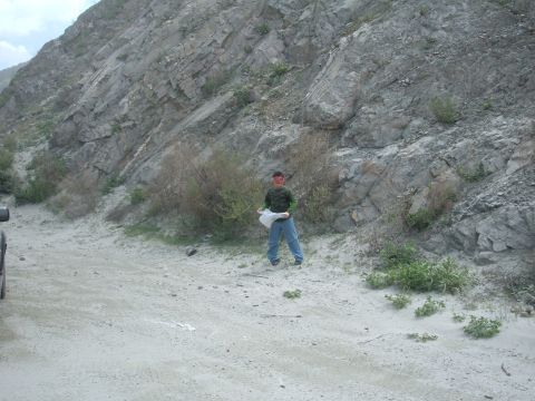 1988 Ford Bronco - A person stands in a dusty, outdoor area with a large rock formation in the background.