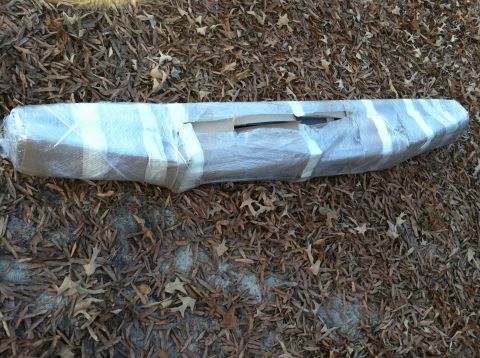 1992 Ford C-350 (Centurion Conversions) - A bumper is wrapped in plastic and tape, lying on a bed of fallen leaves.