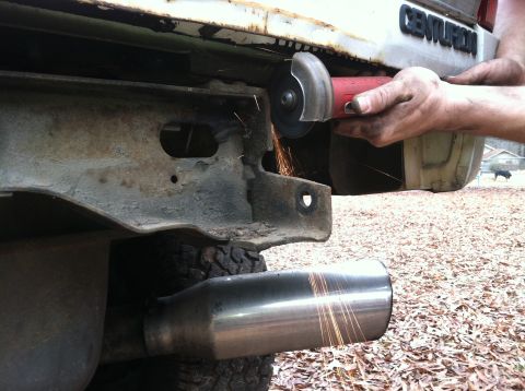 1992 Ford C-350 (Centurion Conversions) - Customization in progress: a rusty bumper is being cut with an angle grinder, with 'Centurion' lettering visible on the vehicle body.