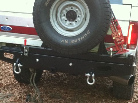 1992 Ford C-350 (Centurion Conversions) - Rear view of a Ford Bronco showing a custom bumper, spare tire, and Hi-Lift jack.