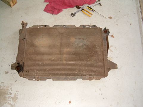 1991 Ford Bronco - A used radiator, likely from an older vehicle, is shown on a workshop floor with tools nearby.