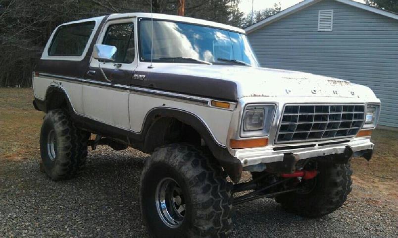 1979 Ford Bronco with lifted suspension and large off-road tires, parked on gravel
