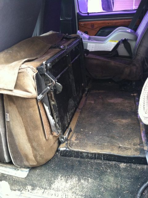 1992 Ford C-350 (Centurion Conversions) - The interior of a van shows a folded seat and a child's car seat, suggesting a utilitarian or family use.