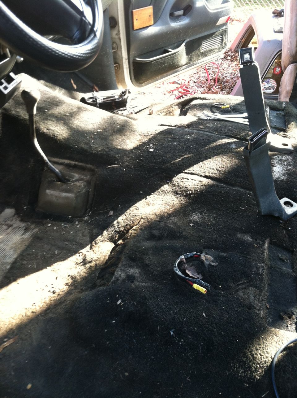 Interior of a truck with carpet removed, showing the floor, dashboard, and seatbelt