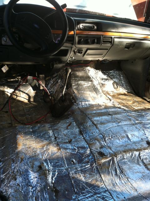 1992 Ford C-350 (Centurion Conversions) - The interior of a truck is shown with the floor covered in soundproofing material and some wiring exposed.