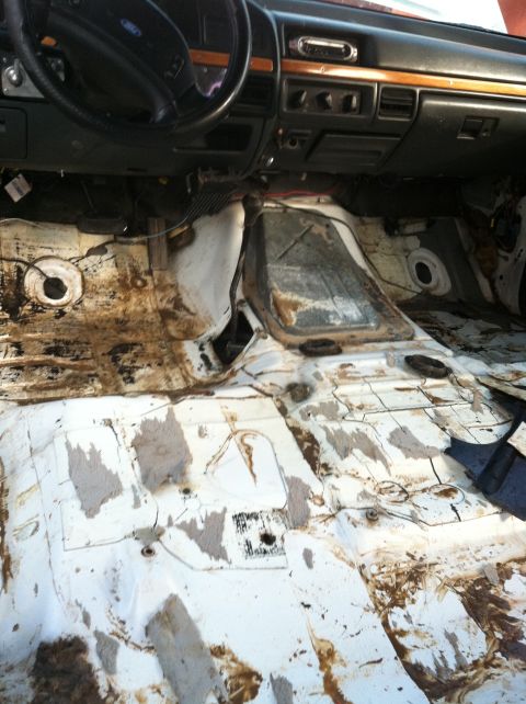 1992 Ford C-350 (Centurion Conversions) - The interior floor of a truck is exposed after carpet removal, revealing significant rust and dirt.