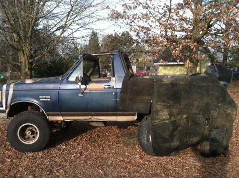 1992 Ford C-350 (Centurion Conversions) - A blue pickup truck with a "Bronco" badge is parked outdoors, its rear covered by a tarp.
