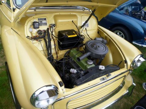 1969 MINI Cooper - The engine bay of a yellow classic car is open, revealing its green engine block and various components. Another car is visible in the back…