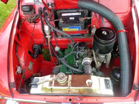 1969 MINI Cooper - The engine bay of a red 1969 MINI Cooper shows its green engine block and chrome radiator.