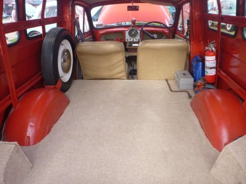 1969 MINI Cooper - This 1969 MINI Cooper interior features beige seats, a spare tire mounted on the side, and a fire extinguisher.