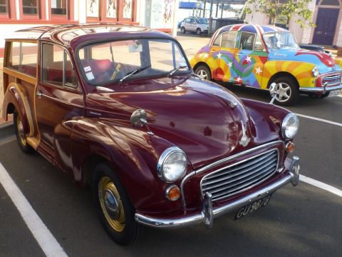 1969 MINI Cooper - A maroon wood-paneled station wagon is parked in front of a brightly decorated car with a Union Jack theme.