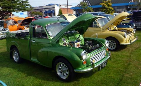 1969 MINI Cooper - A green pickup truck is displayed with its hood open at an outdoor car show.