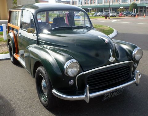 1969 MINI Cooper - A classic green woodie station wagon is parked on a street, a prominent chrome bumper and grille.