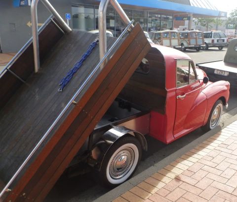 1969 MINI Cooper - A red pickup truck with a wooden bed is parked on a street, with other vehicles visible in the background.