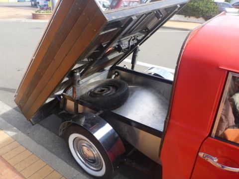 1969 MINI Cooper - A red pickup truck's bed is open, revealing its wooden interior and a spare tire.