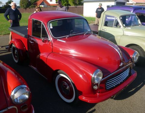 1969 MINI Cooper - A red pickup truck is parked at an outdoor event with other vehicles.