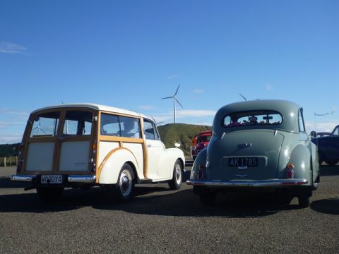1969 MINI Cooper - Two vintage vehicles, a woody wagon and a grey sedan, are parked outdoors under a clear blue sky.